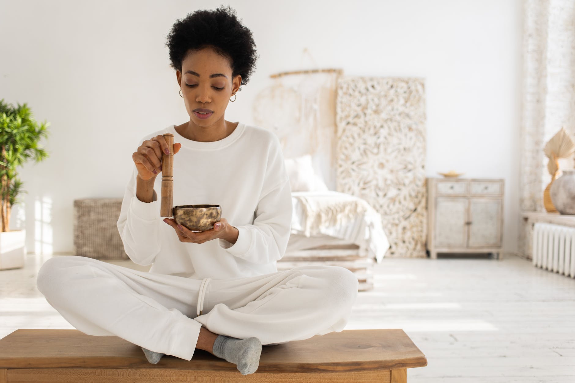 a woman using a singing bowl while sitting - positive healing quotes